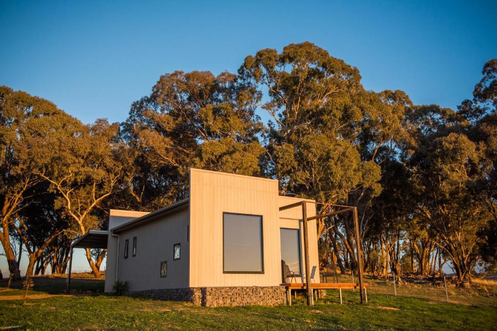 una casa modular con un banco frente a los árboles en Dragonfly Cottages en Orange