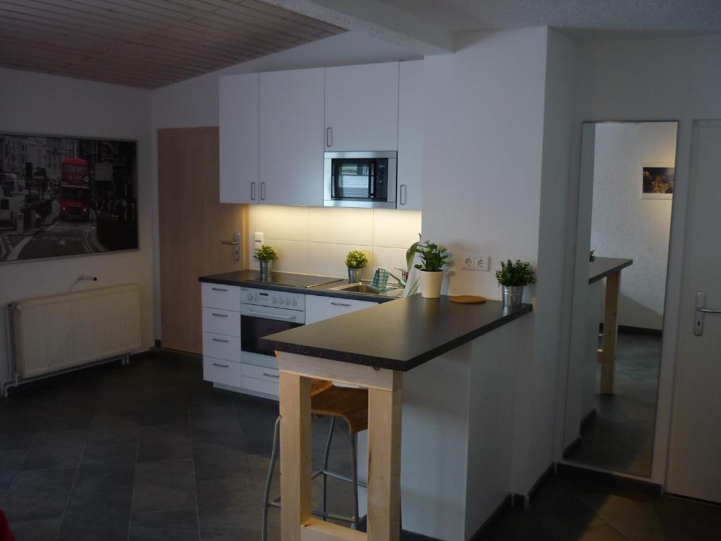 a kitchen with white cabinets and a black counter top at Wohnen im ehemaligen Kaminstudio mit Klimaanlage in Lutherstadt Wittenberg