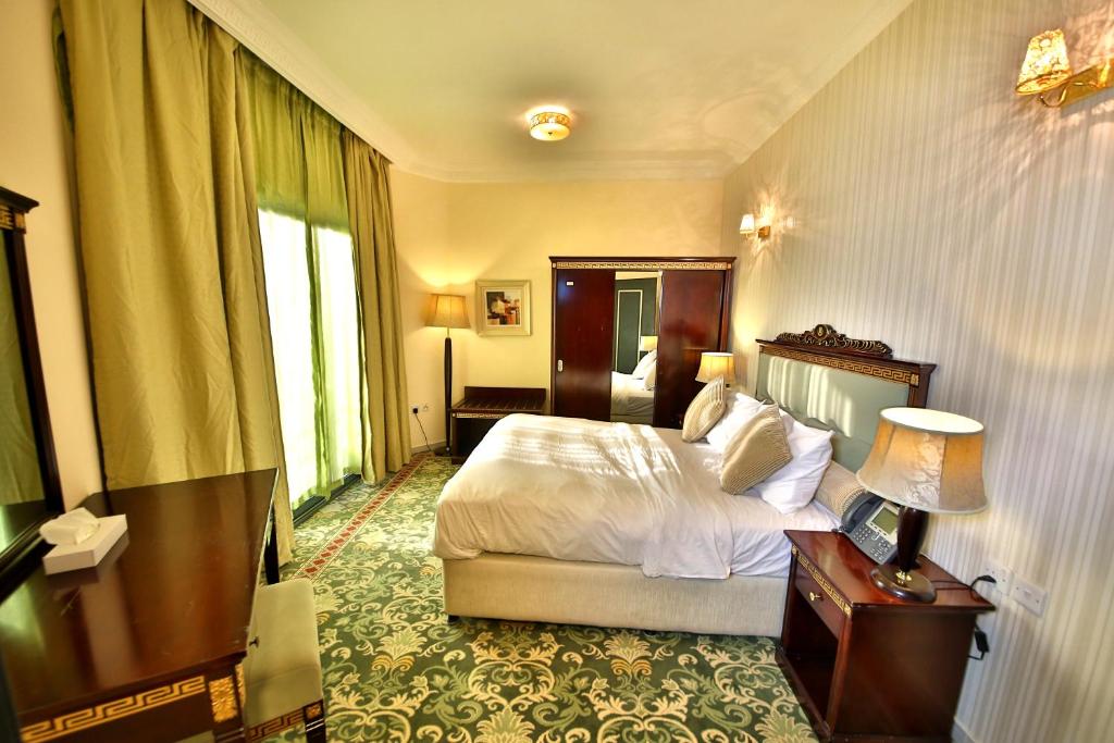 1 dormitorio con 1 cama, 1 mesa y 1 lámpara en Midtown Furnished Apartments, en Ajman