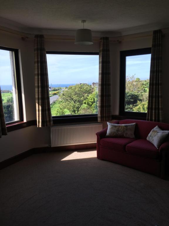 a living room with a couch and two large windows at The Greannan Bed & Breakfast in Blackwaterfoot