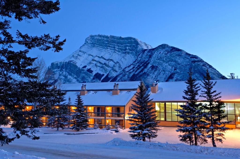 a hotel in the snow with a mountain in the background at Douglas Fir Resort & Chalets in Banff