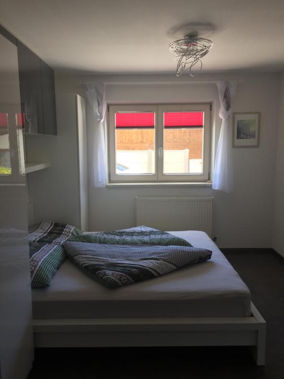 Bett in einem Schlafzimmer mit Fenster in der Unterkunft Hausers Ferienwohnungen in Zell am Ziller