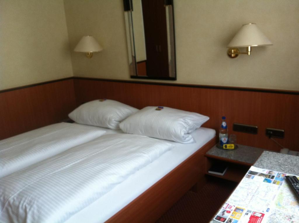 ein Bett mit zwei Kissen in einem Hotelzimmer in der Unterkunft Hotel Hauser an der Universität in München