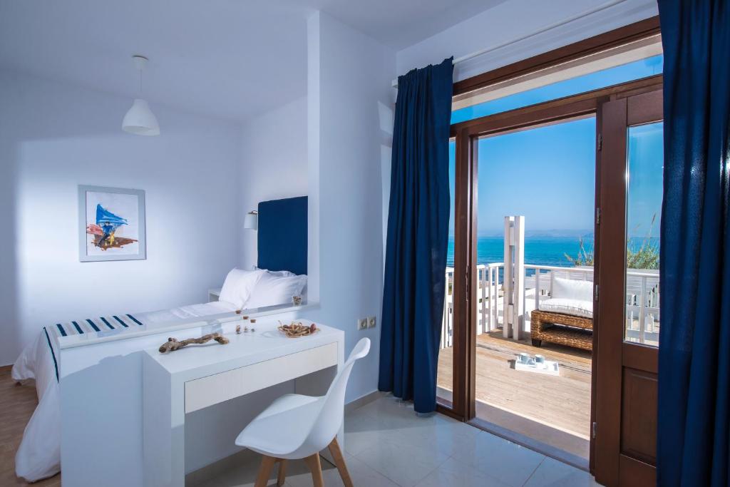 a bedroom with a desk and a view of the ocean at Golden Grain Beachfront Suites in Kokkini Khanion