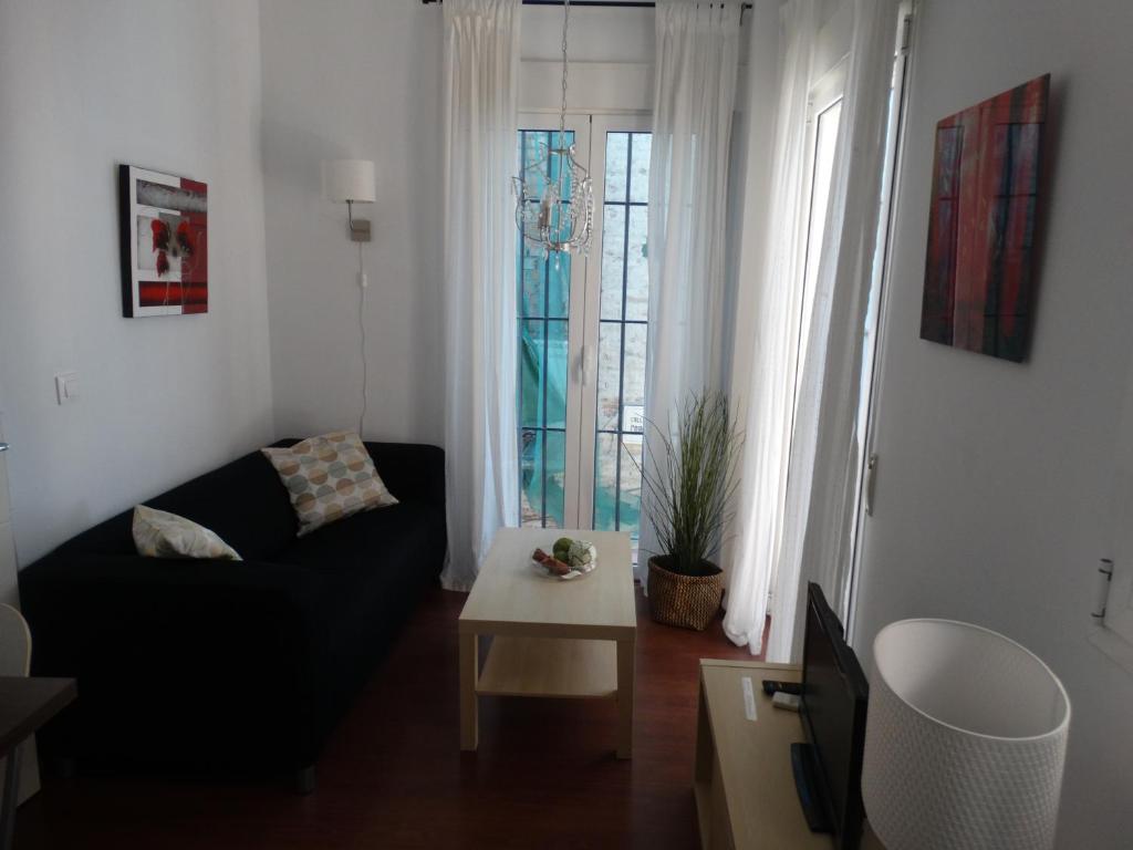 a living room with a black couch and a table at Málaga Apartamentos - Pozos Dulces, 22 in Málaga
