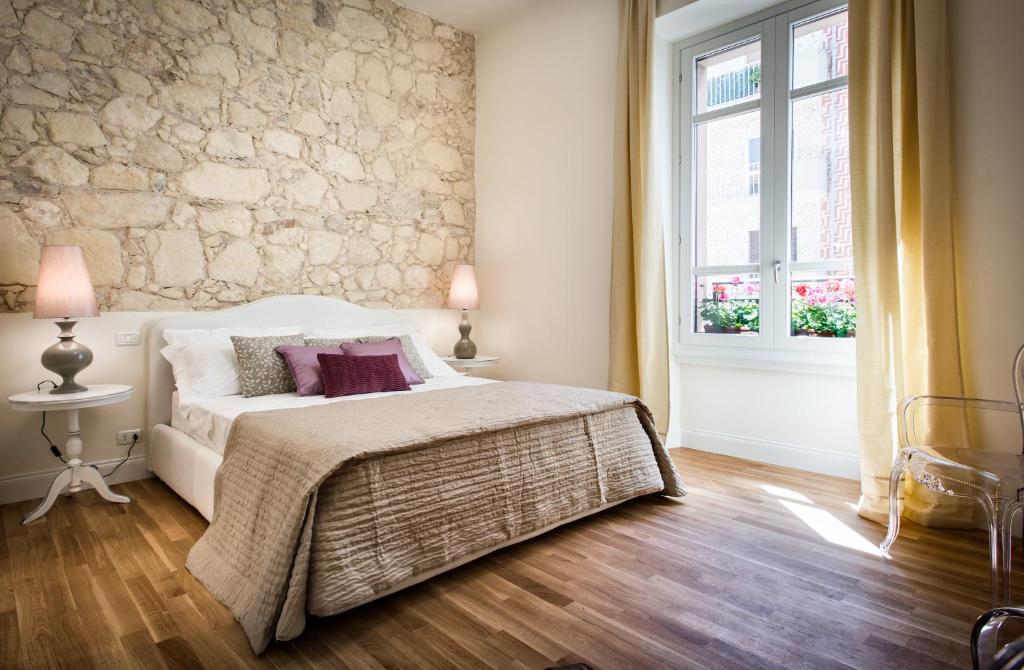 een slaapkamer met een wit bed en een stenen muur bij BB22 Cagliari in Cagliari