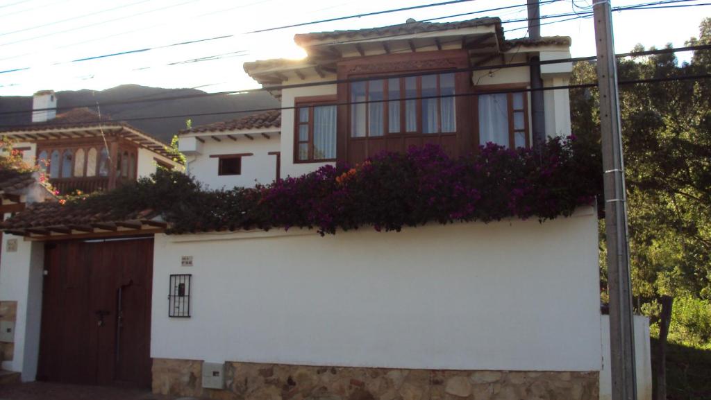 Una casa blanca con flores púrpuras a un lado. en Casa Leo en Villa de Leyva