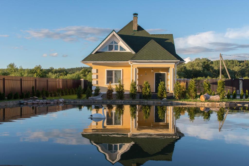 a small yellow house with its reflection in the water at Family Complex Zastava u Oki in Velegozh