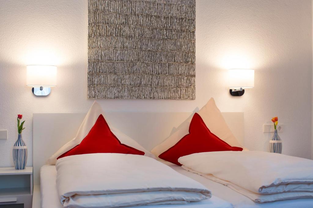 a bedroom with two red pillows on a bed at Hotel Mille Stelle City in Heidelberg