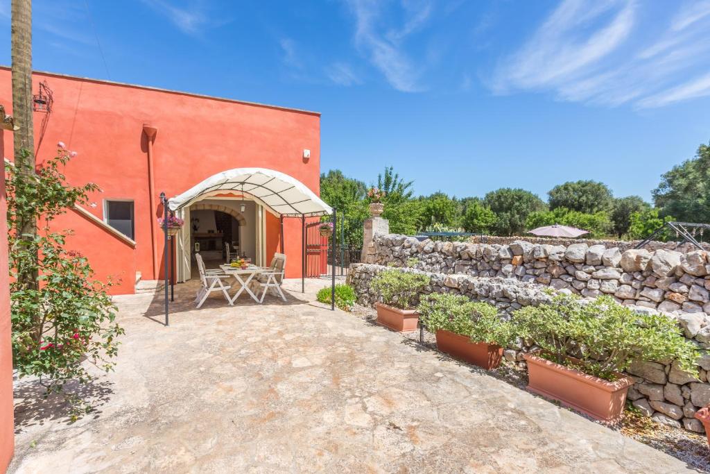 um edifício de tijolos vermelhos com uma mesa e uma parede de pedra em La Corte Della Masseria em San Vito dei Normanni