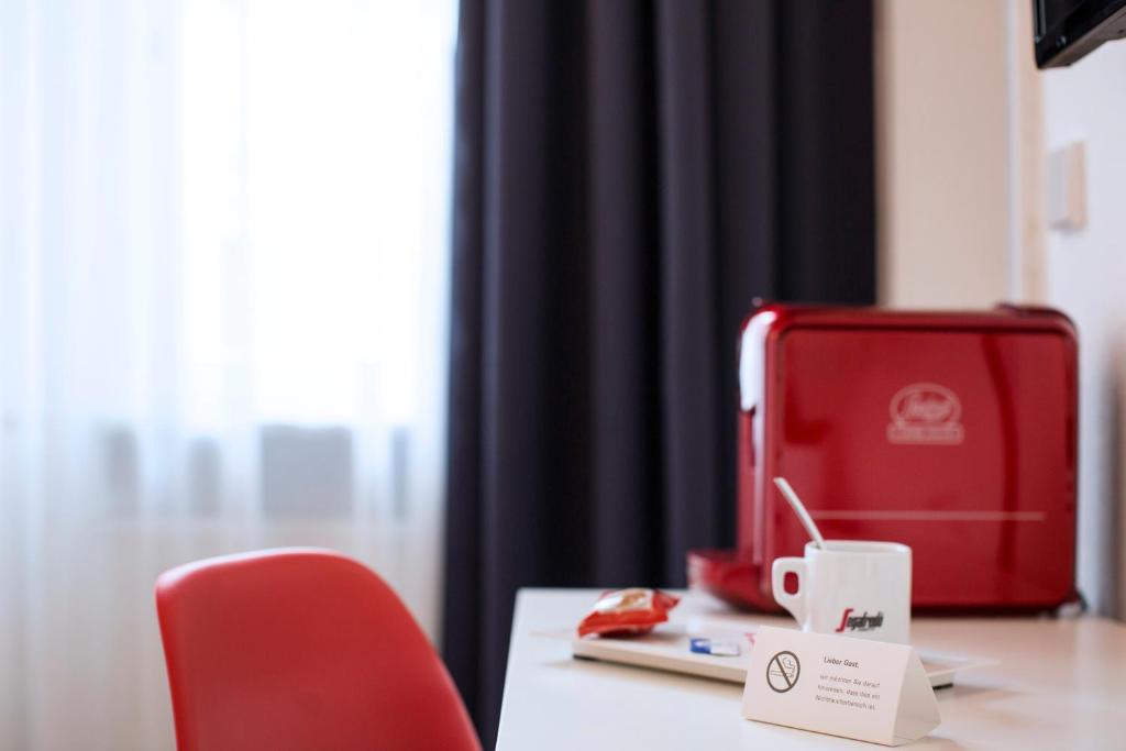 a desk with a red briefcase and a red chair at Hotel Mille Stelle City in Heidelberg