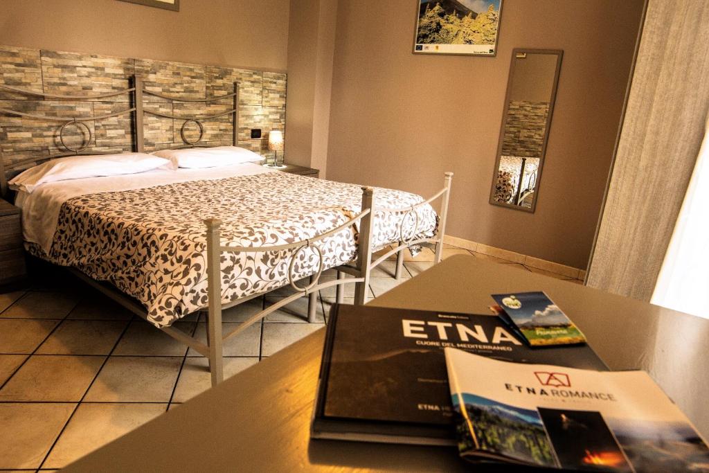 a bedroom with a bed and a table with a book at Sotto Il Vulcano in Nicolosi