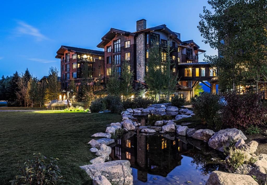 a large house with a pond in front of it at Hotel Terra Jackson Hole, a Noble House Resort in Teton Village