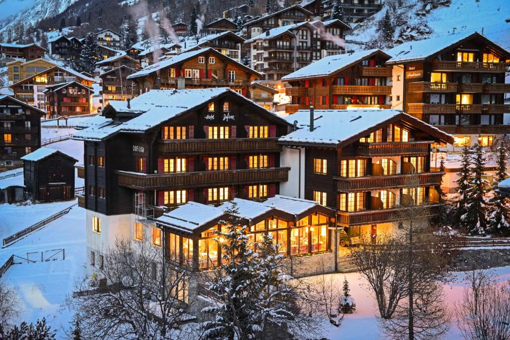 Hotel Dufour Alpin Superior - Adults only في زيرمات: مبنى كبير مع إضاءة في الثلج
