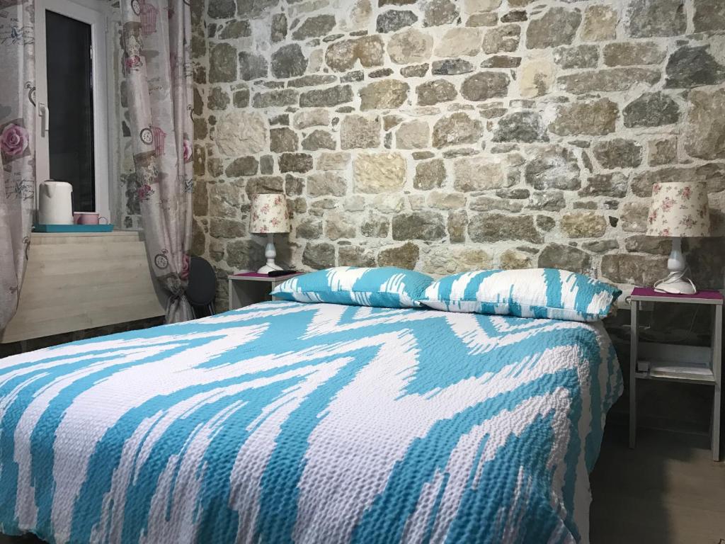 1 dormitorio con cama y pared de piedra en Room N&M - Diocletians palace, en Split