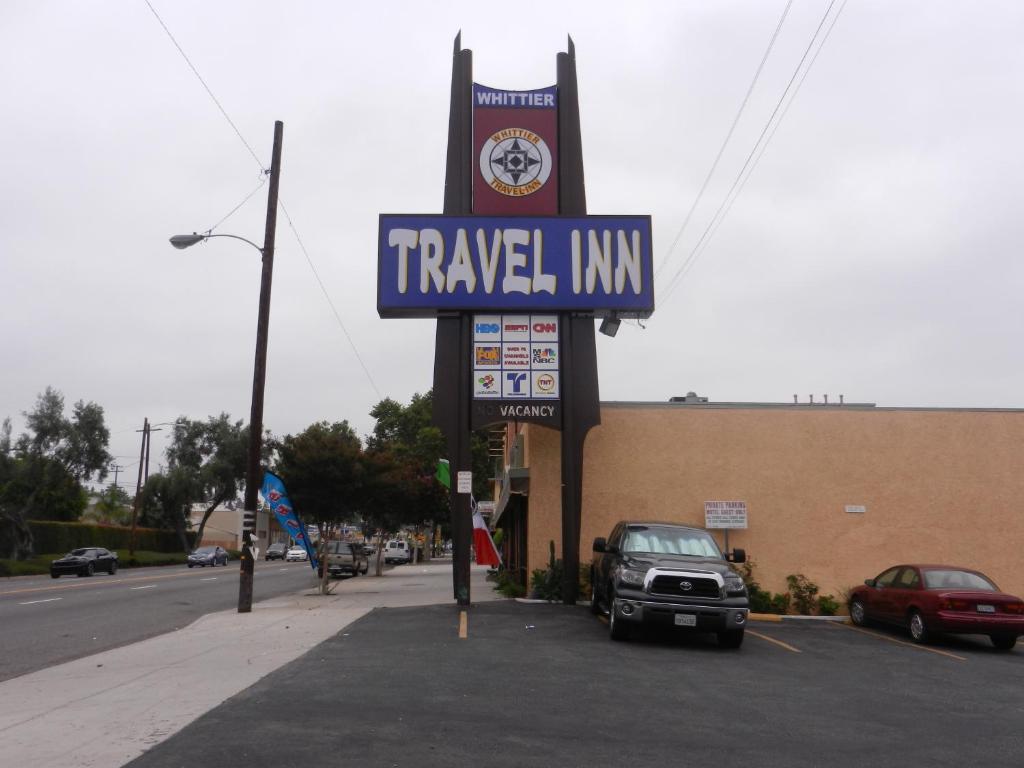 una señal para una posada de viajes en un estacionamiento en Whittier Travel Inn en Whittier