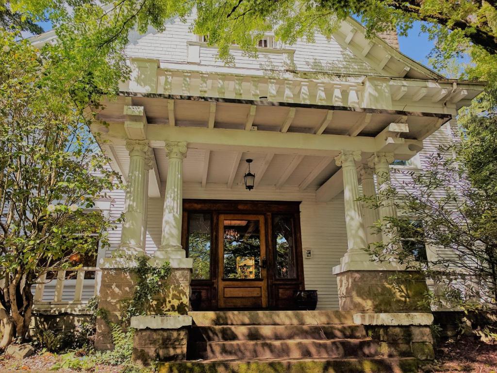 una veranda anteriore di una casa bianca con porta in legno di Evermore Guesthouse a Portland