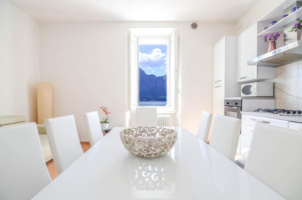 a white kitchen with a large white table and chairs at Appartamenti Il Sogno in Bellagio
