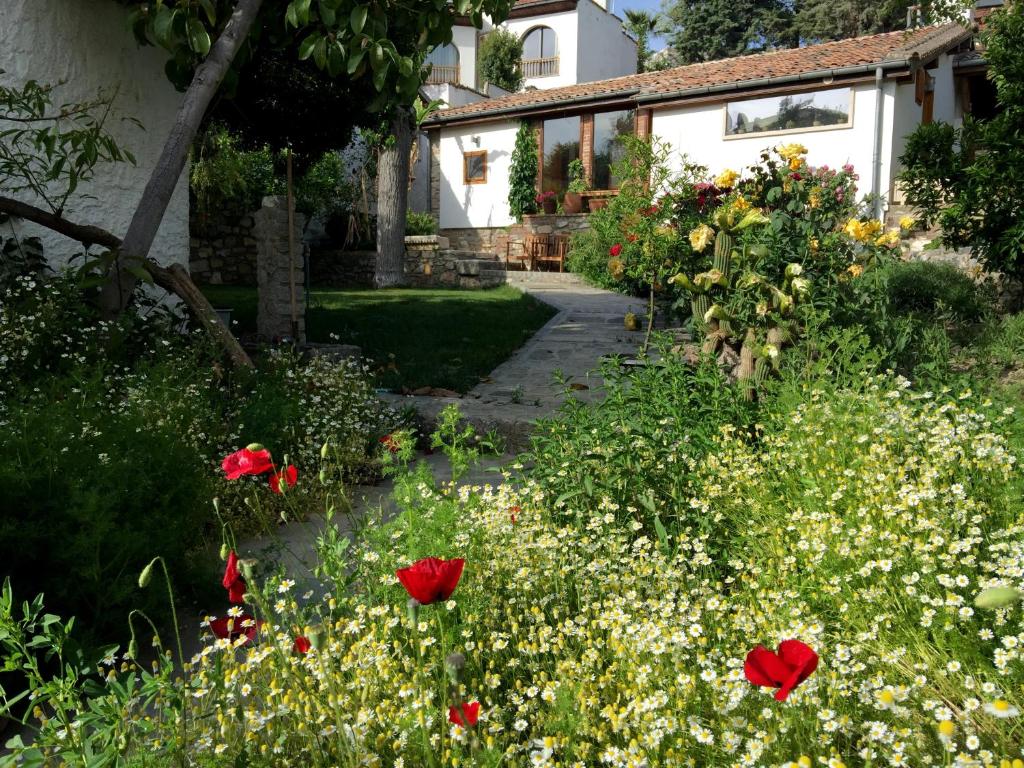 a garden with red flowers in front of a house at Garden House in Selçuk