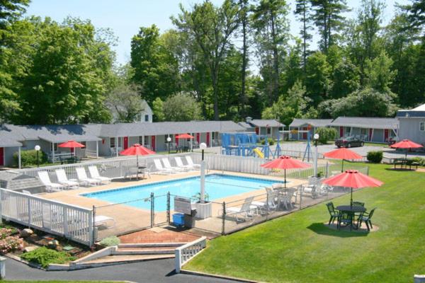 a large swimming pool with red umbrellas and tables at Barberry Court Motel &Cabins in Lake George