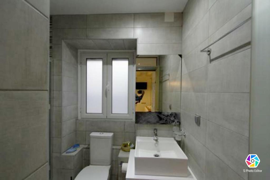 uma casa de banho com um lavatório, um WC e uma janela. em Helens Apartment em Corfu Town