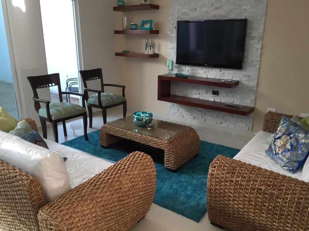 a living room with a couch and chairs and a television at Apartamento en la playa en Mazatlán in Mazatlán