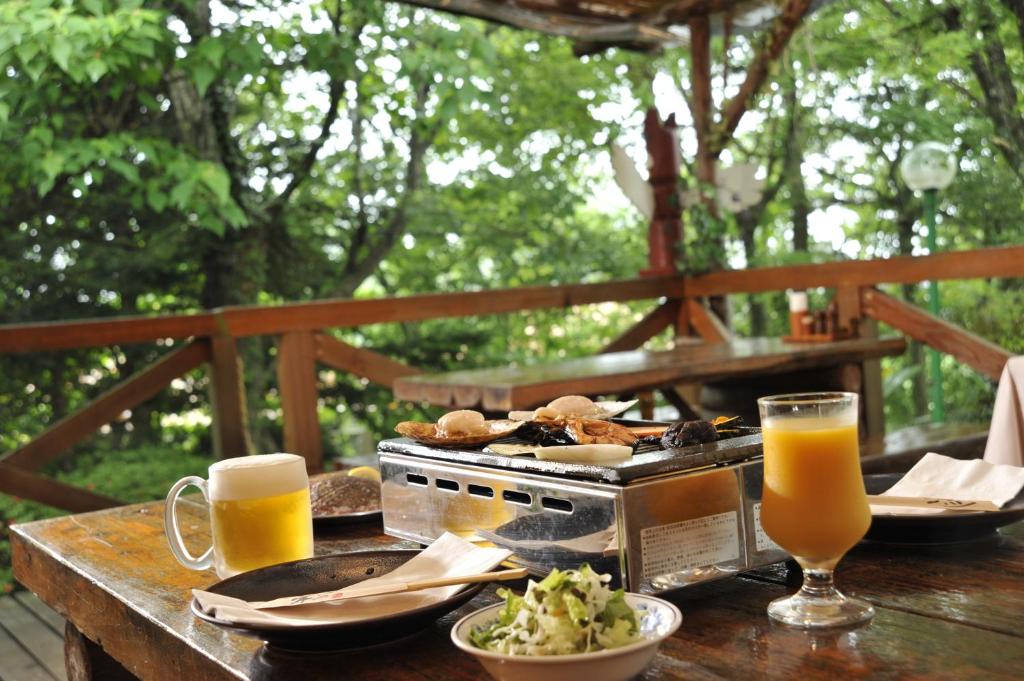 una mesa con platos de comida y vasos de zumo de naranja en Pension Totem Pole, en Ito