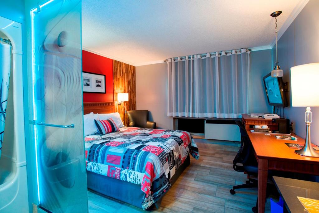 a hotel room with a bed and a desk and a desk at Amosphère Complexe in Amos