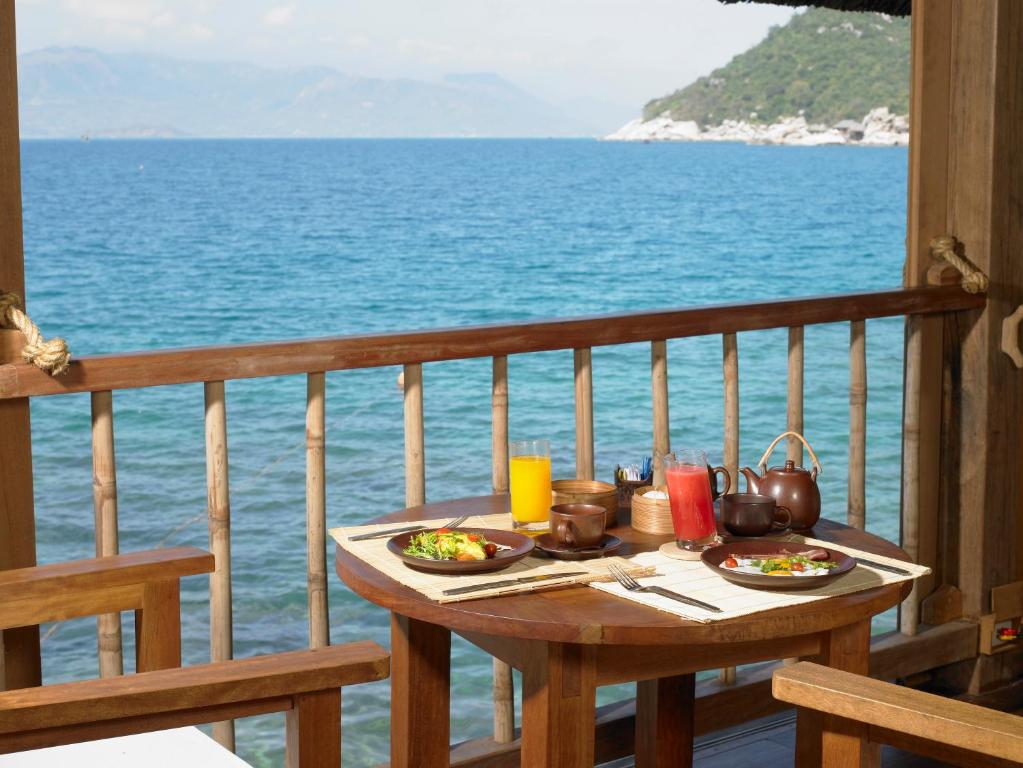 a table with plates of food on a balcony with the ocean at Six Senses Ninh Van Bay in Ninh Van Bay