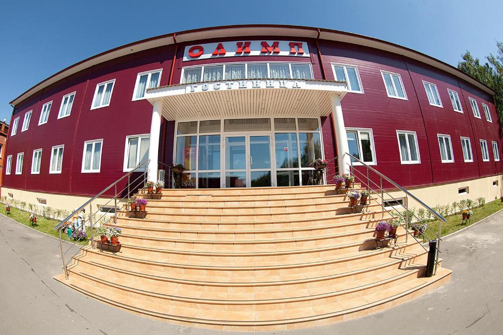 a large red building with stairs in front of it at Hotel Olimp in Vyalki