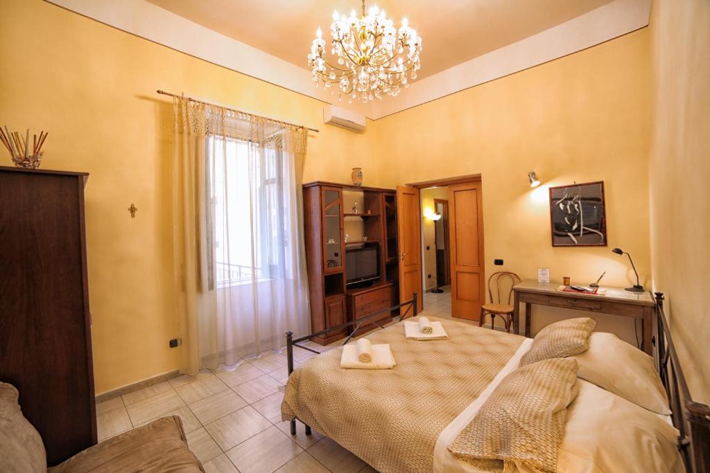 a bedroom with a bed and a table and a chandelier at La Corte in Cava deʼ Tirreni