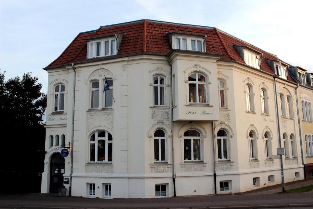 ein großes weißes Gebäude mit rotem Dach in der Unterkunft The Avalon Hotel in Schwerin