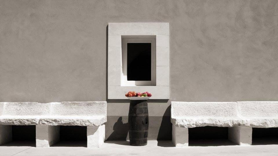 dos bancos sentados junto a una pared con un tazón de fruta en Terre di Senia en Chiaramonte Gulfi