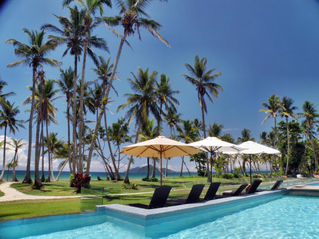 una piscina en la playa con palmeras y sombrillas en Castaways Resort & Spa On Mission Beach en Mission Beach