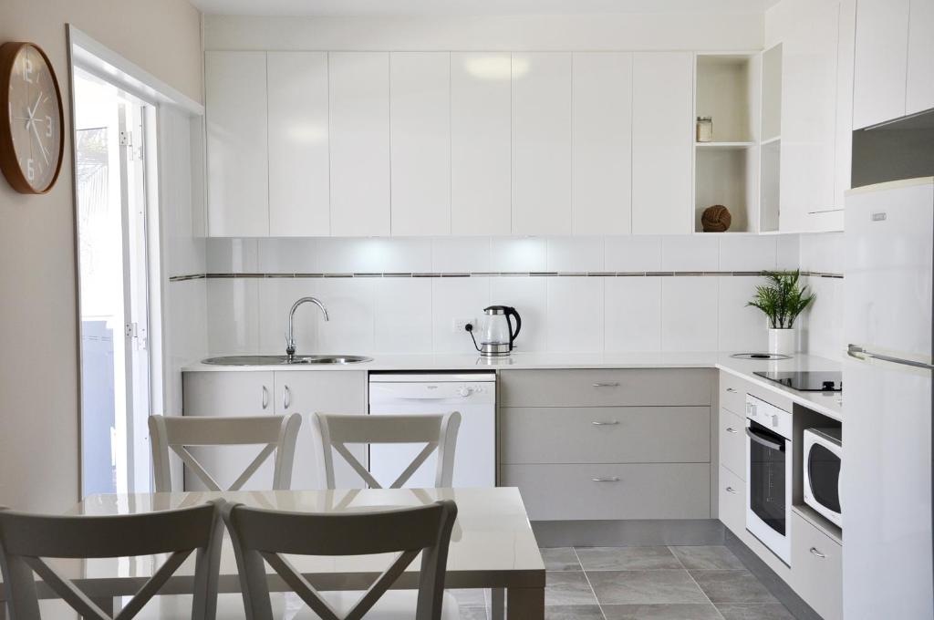 a kitchen with white cabinets and a table and chairs at Angelwaters in Townsville
