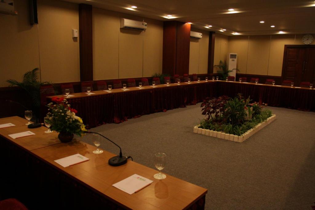 una sala conferenze con tavoli, sedie e piante di Syariah Arini Hotel a Solo