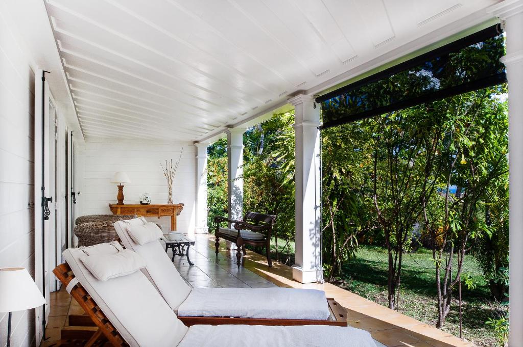 una veranda con mobili bianchi e ampie finestre di Senteur Vanille a Saint-Gilles-les Bains