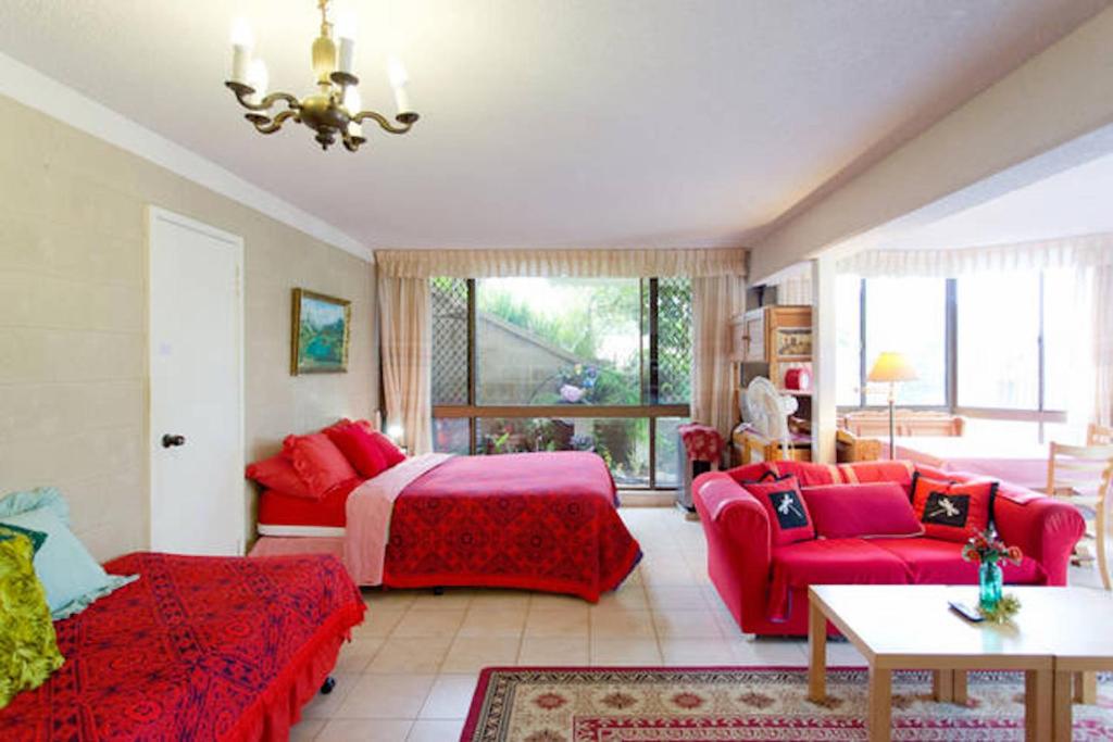 a bedroom with a red bed and a red couch at Beach Haven Studio in Coogee