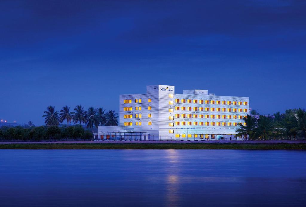a large building with lights on in front of the water at Hotel Naveen Lakeside in Hubli