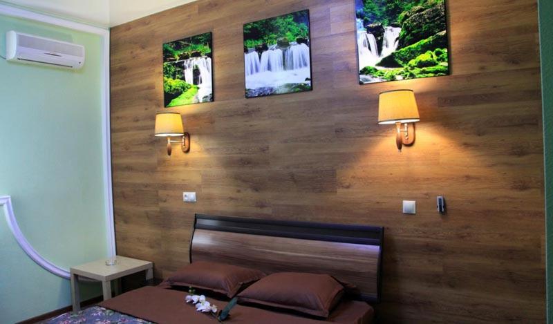 a bedroom with a wooden wall with three pictures on it at Hotel Sfera Barnaul in Barnaul
