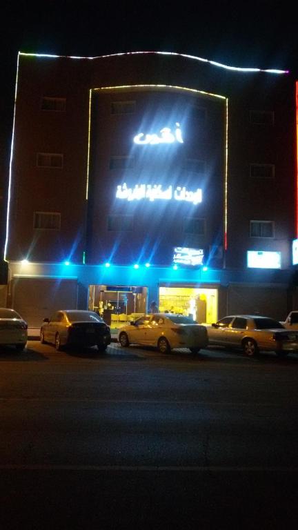 three cars parked in front of a theater at night at Avene For Furnished Residential Units in Ad Dawādimī