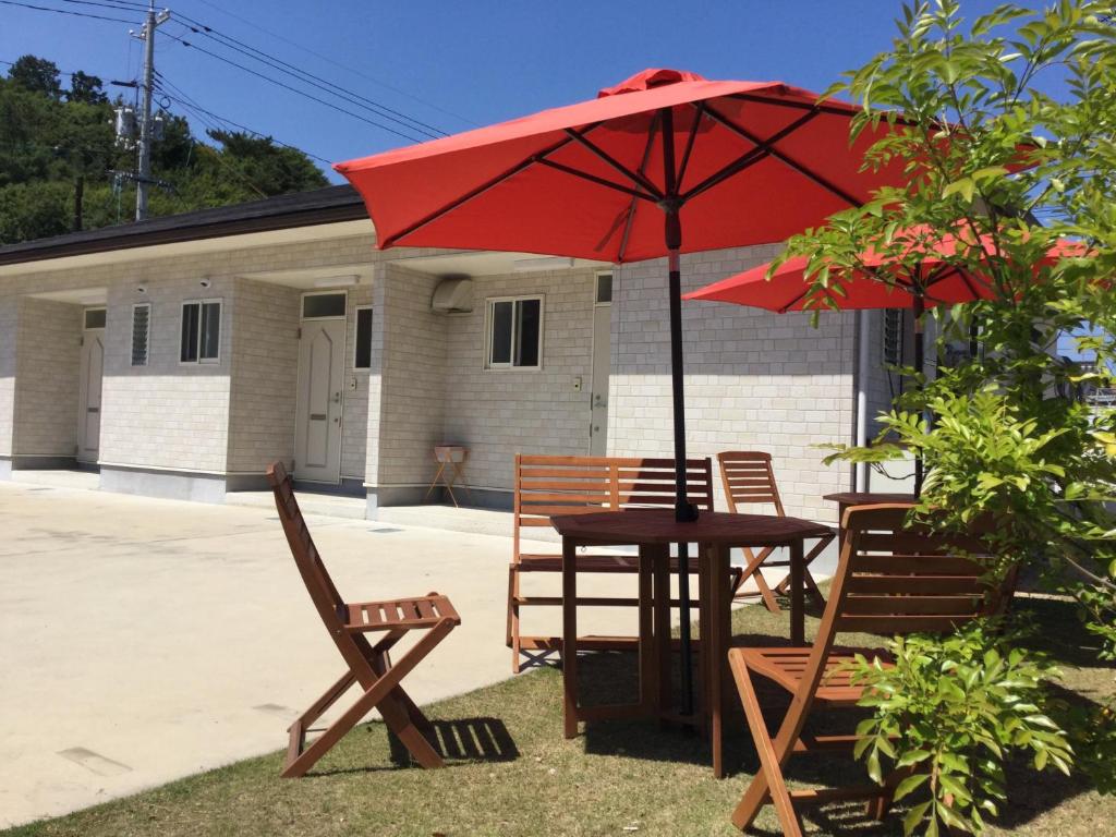 a table and chairs with a red umbrella at La Curación in Naoshima