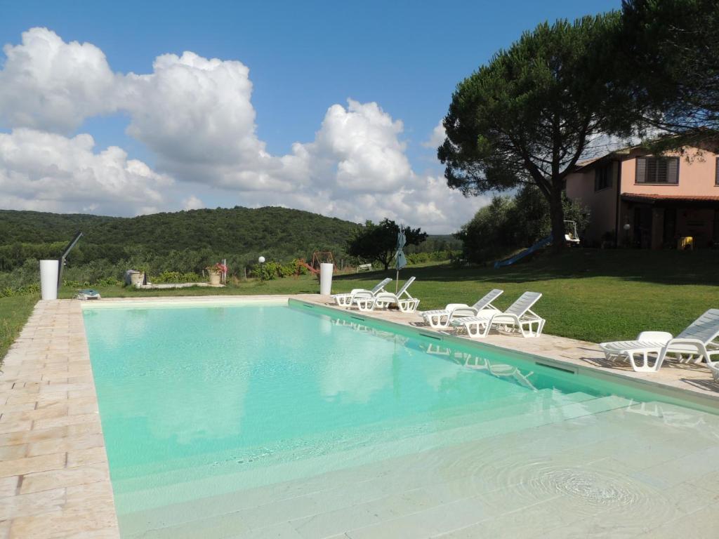 ein großer Pool mit Stühlen und ein Haus in der Unterkunft Agriturismo Podere Borgognano in Massa Marittima