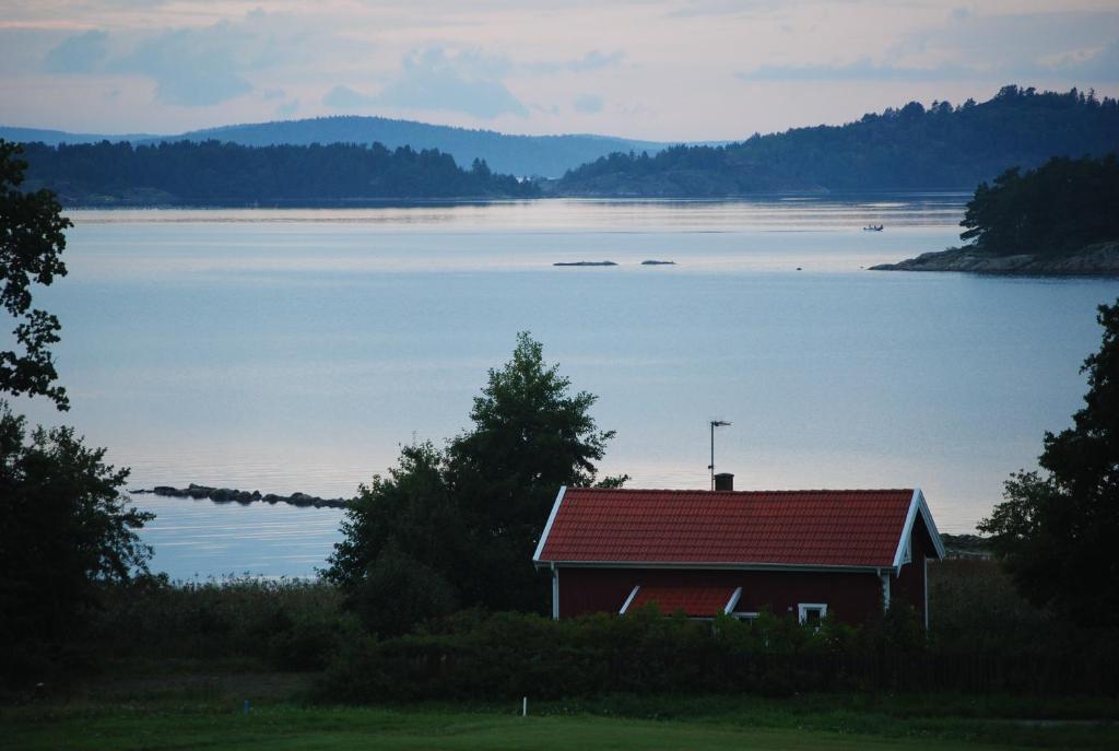 una casa con techo rojo junto a un lago en Anfasteröd Gårdsvik - Sjöstugan en Ljungskile