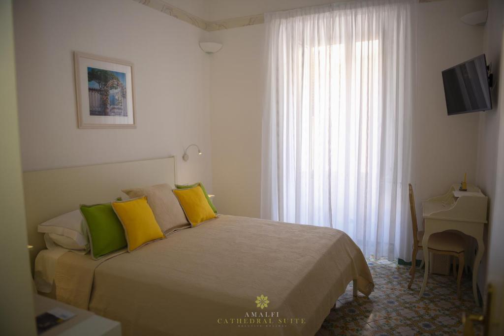 a bedroom with a bed with yellow and green pillows at Amalfi Cathedral Suite in Amalfi