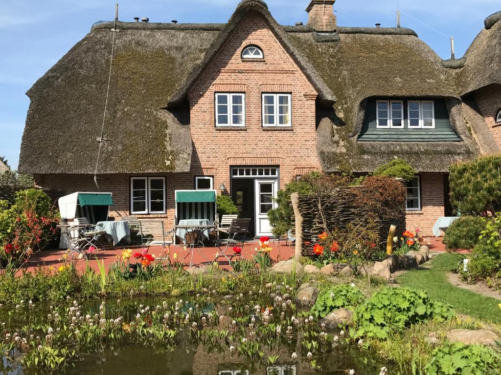 una casa antigua con techo de paja y jardín en Ulenhof Appartements, en Wenningstedt