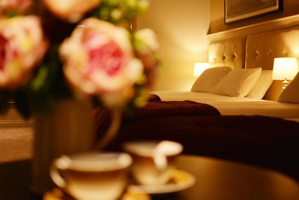 a hotel room with a bed and a table with flowers at Rooms At Rue in Omagh