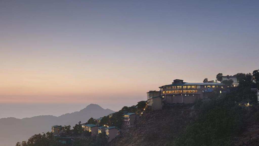 a building on top of a hill at sunset at Sterling Mussoorie in Mussoorie