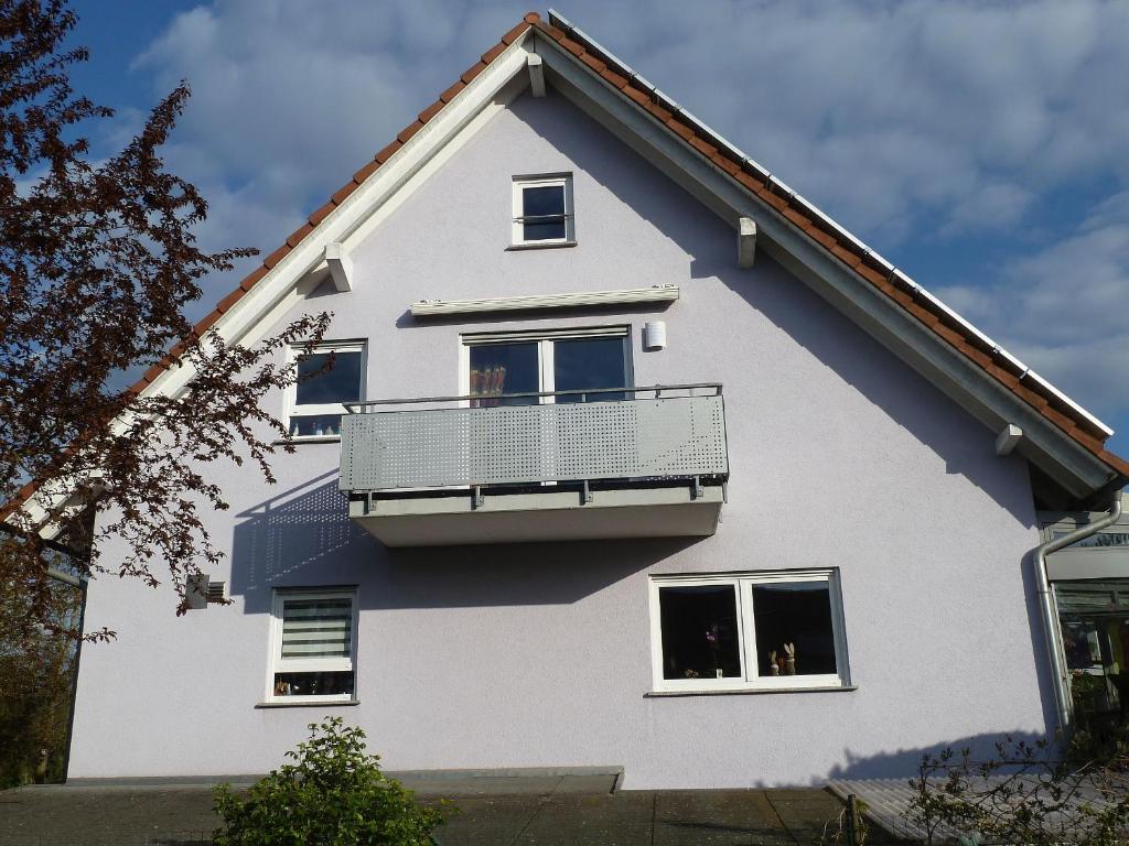 een wit huis met een balkon bij Ferienwohnung Mühlerain in Heitersheim