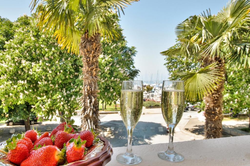 two glasses of champagne and strawberries on a table with palm trees at Boutique Apartman Villa Mediteran in Poreč